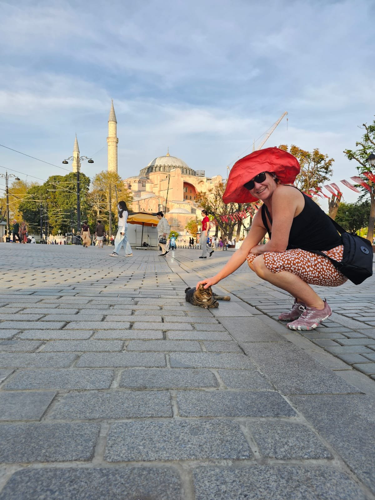 Roshell crouching to feed a street cat in front of the Hagia Sophia in Istanbul