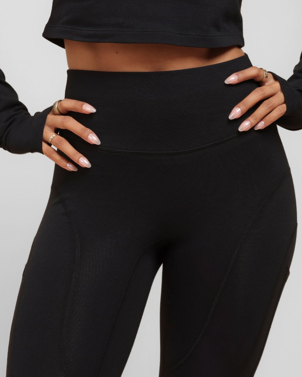 Close view of the wide high waistband on black Breeth Regular Cotton Leggings, hands resting on the hips.